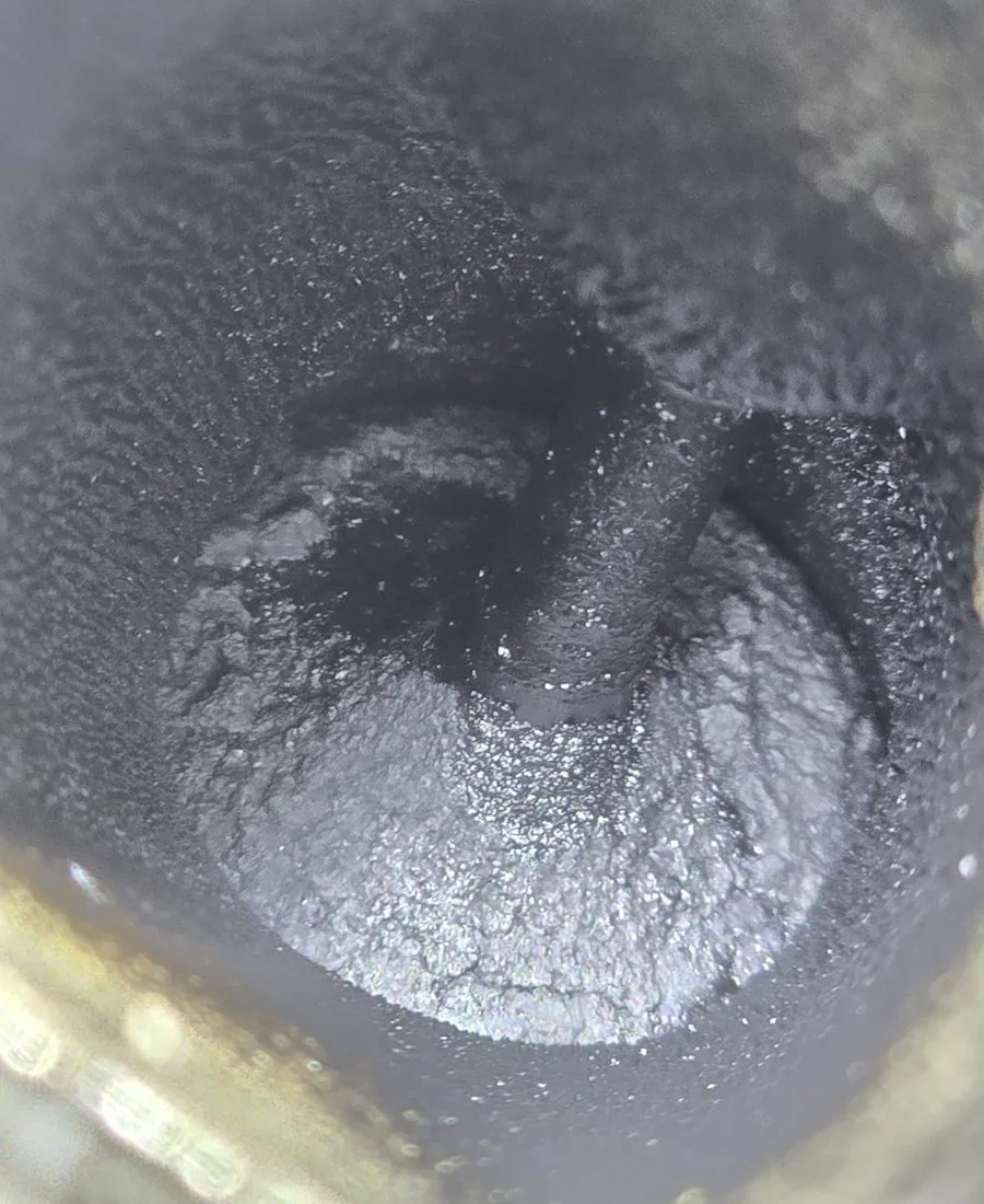 Intake valve with severe carbon deposits — port and valve face heavily fouled, significant restriction